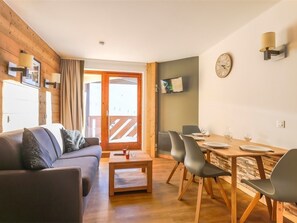 A modern living room with a sofa, coffee table, and dining area with chairs and a table. - Renovated apartment, mountain view - 4 guests (Val Thorens)