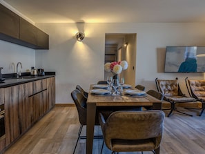 A modern kitchen with a wooden countertop and a dining area with a wooden table set for four. - Practical apartment at the ski slopes - 6 guests (Belle Plagne)