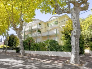 A multi-story residential building with balconies, surrounded by trees and a white fence. - Quiet studio near beach - 3 guests (Arcachon)