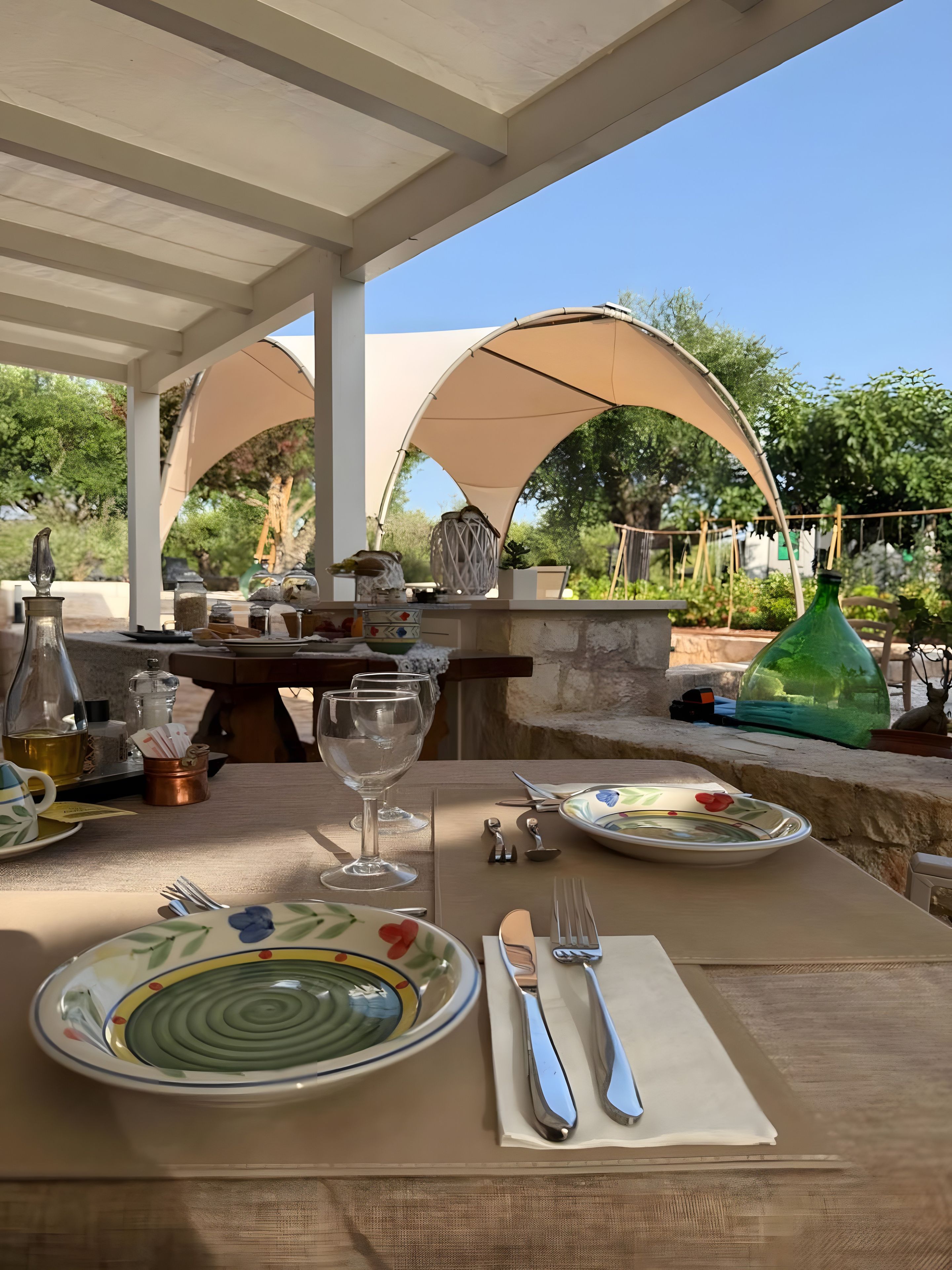 Un espace de restauration en plein air avec une table dressée pour deux personnes, offrant une vue dégagée sur le jardin et les arbres environnants.