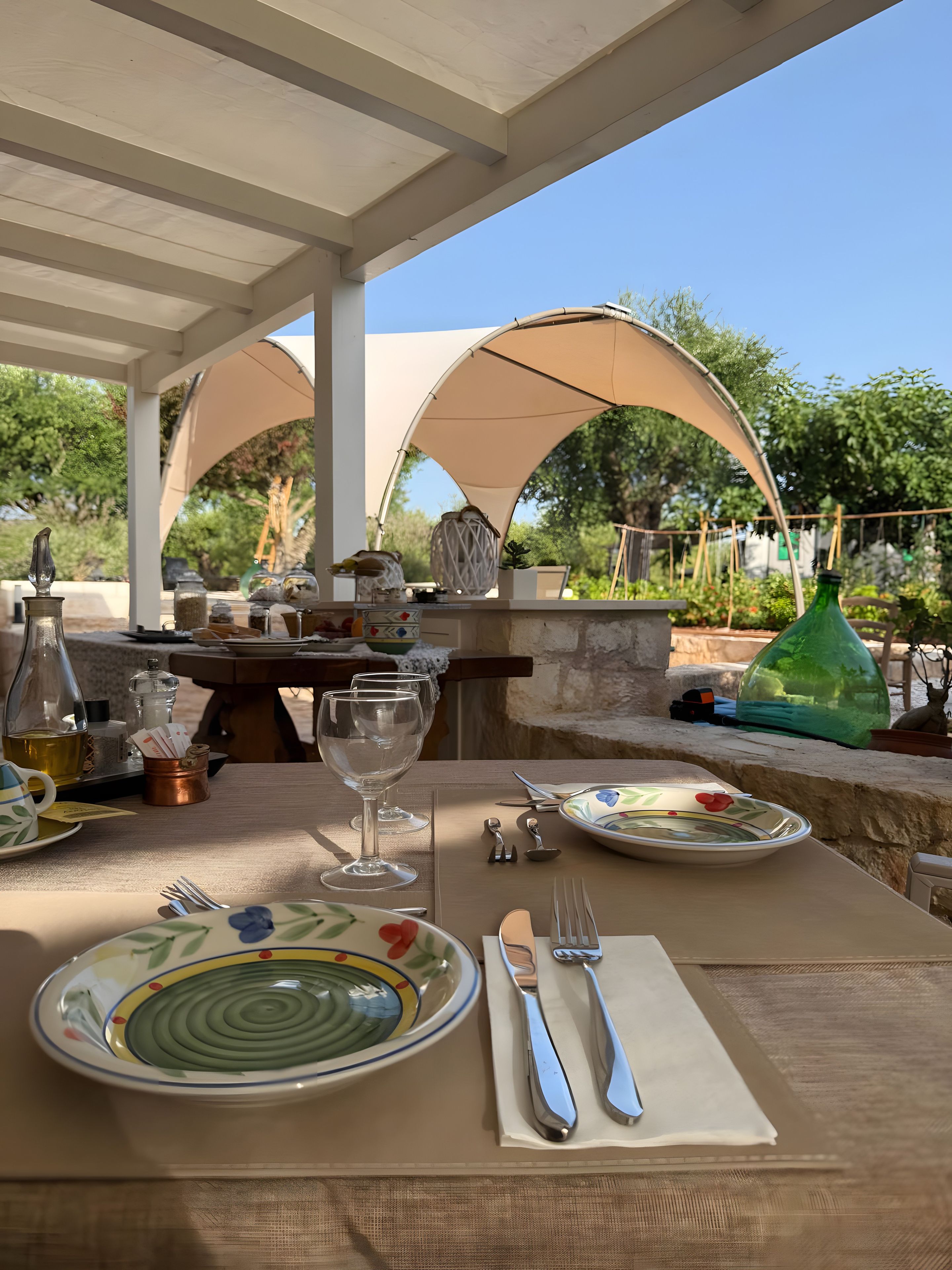 Ein Essbereich im Freien mit einem Tisch für zwei Personen, einer Pergola darüber und Blick auf den Garten.