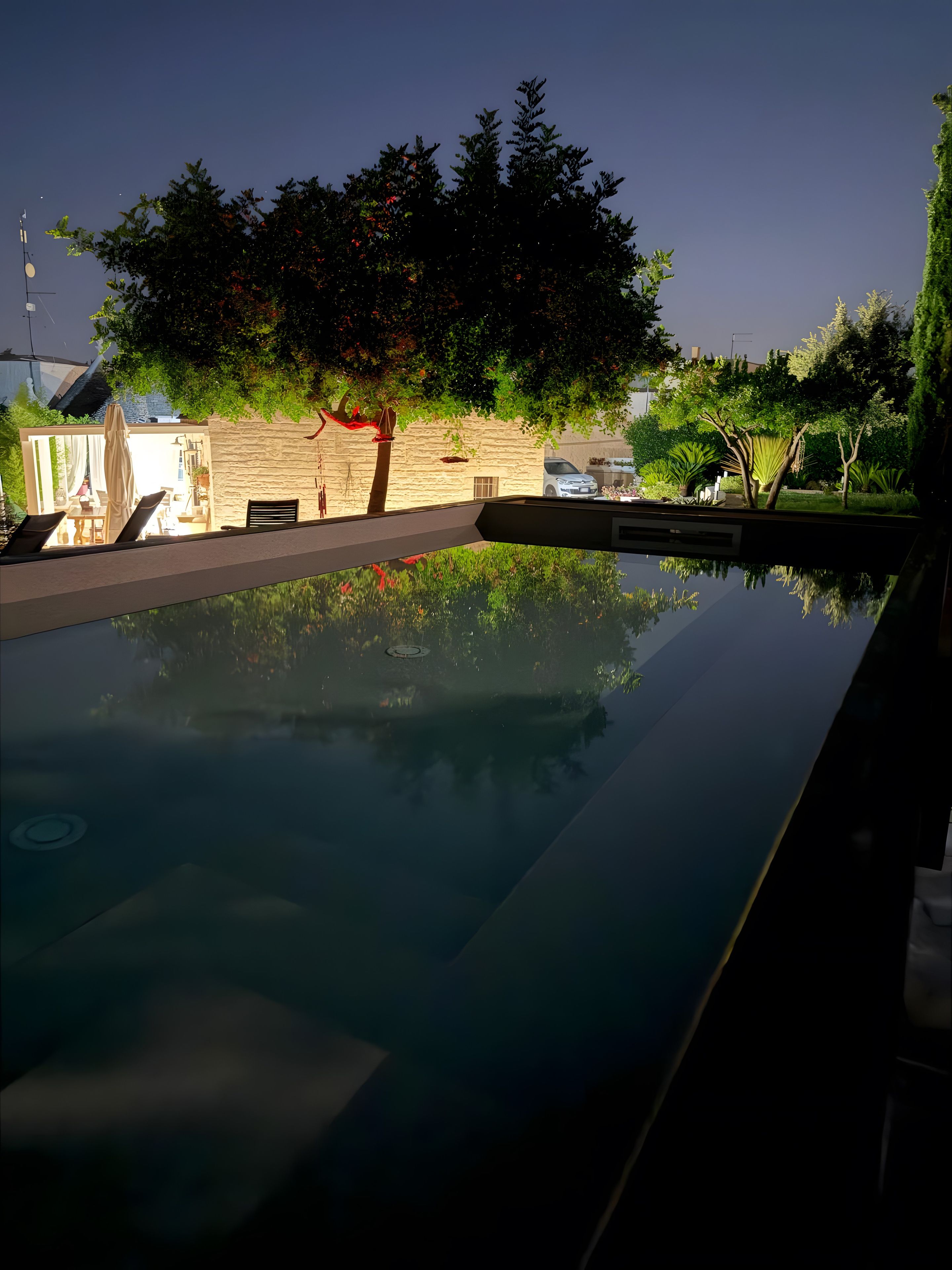 A swimming pool with a stone wall and greenery in the background.