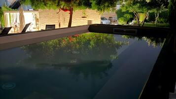 A swimming pool with a stone wall and greenery in the background.