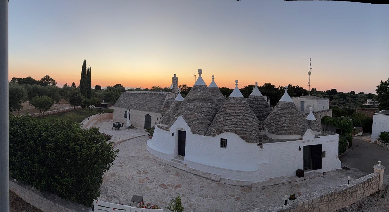 A traditional building with multiple conical roofs, a stone pathway, and a clear sky.