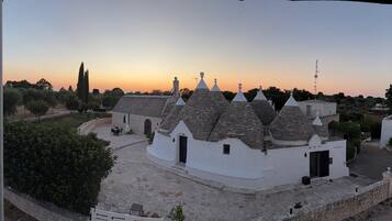 A traditional building with multiple conical roofs, a stone pathway, and a clear sky.