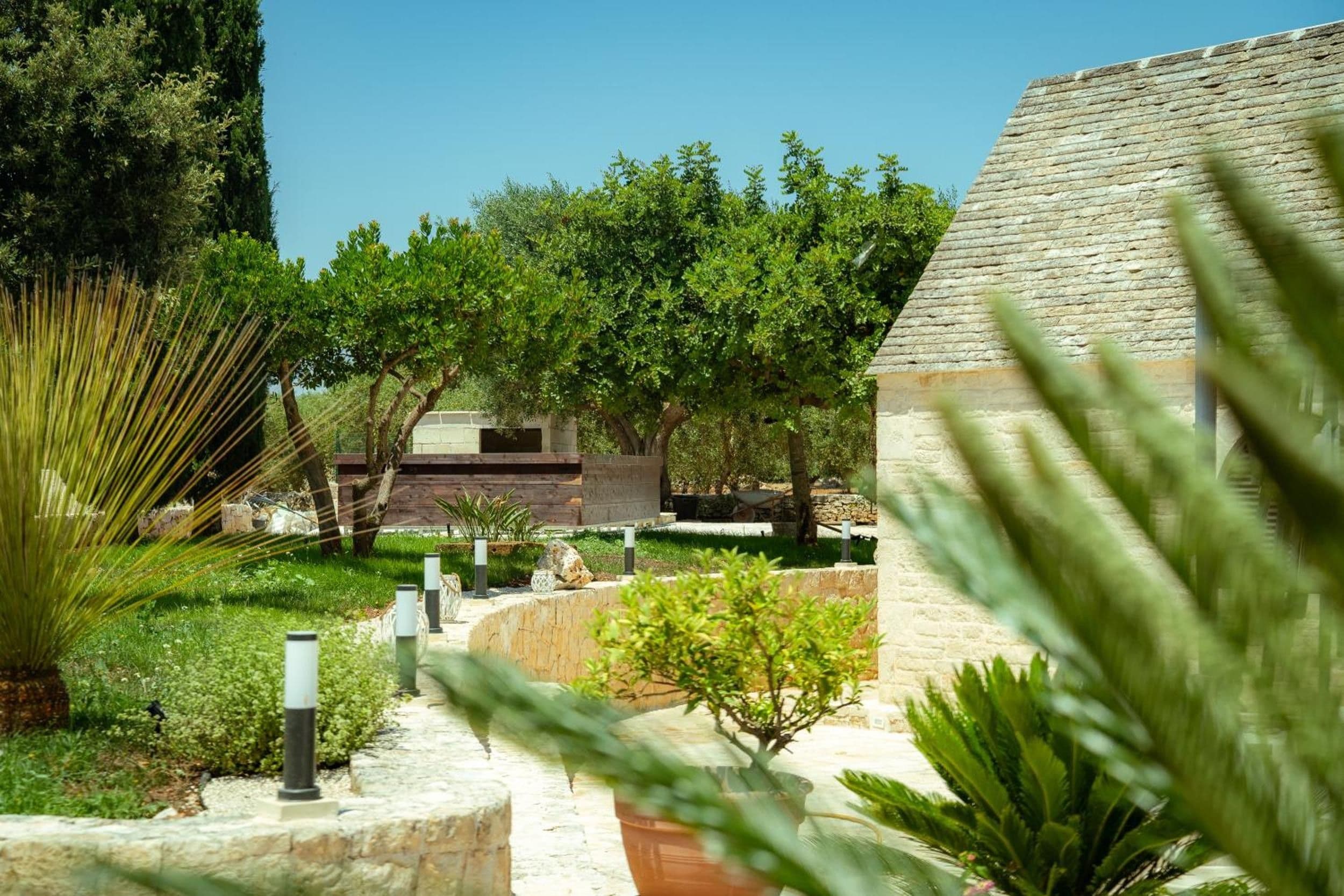 A landscaped garden with a stone pathway, various shrubs, and trees.
