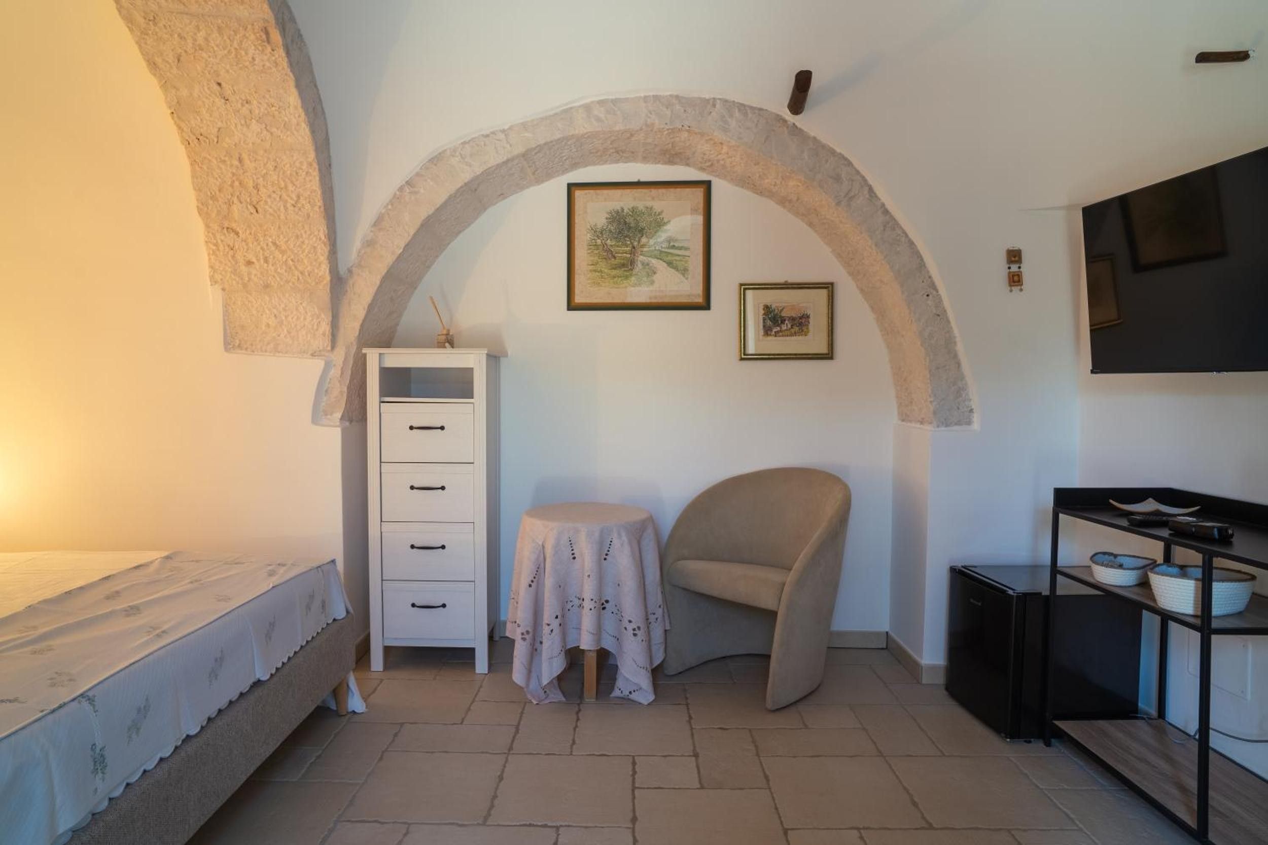 A room with a bed, a small table, a chair, a cabinet, and a TV.