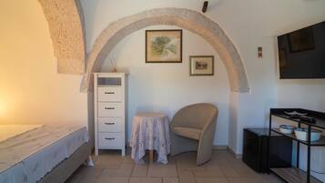 A room with a bed, a small table, a chair, a cabinet, and a TV.