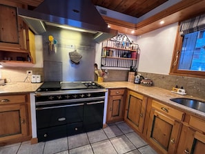 A kitchen with a stove, oven, and various kitchen utensils on the countertop. - Typical Chalet 6 Rooms, Garden, 8 Pers (Saint-Martin-de-Belleville)