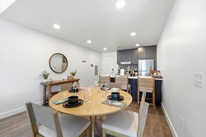 A modern dining area with a round table, chairs, and a kitchen in the background. - Pioche Basecamp | Deer Valley + Mountain Views (Park City)