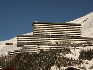 A multi-story hotel with a modern design, located in a snowy mountainous area. - Bright studio, south balcony, mountain view - 3 guests (Les Menuires)