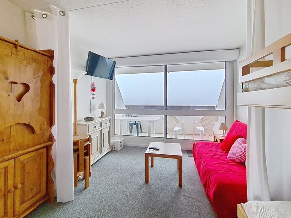 Ein Zimmer mit einem Bett, einem Schreibtisch, einem Fernseher und einem Fenster.