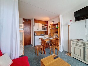 A compact living space with a kitchenette, a dining area, a TV, and a small seating area. - Bright studio, south balcony, mountain view - 3 guests (Les Menuires)
