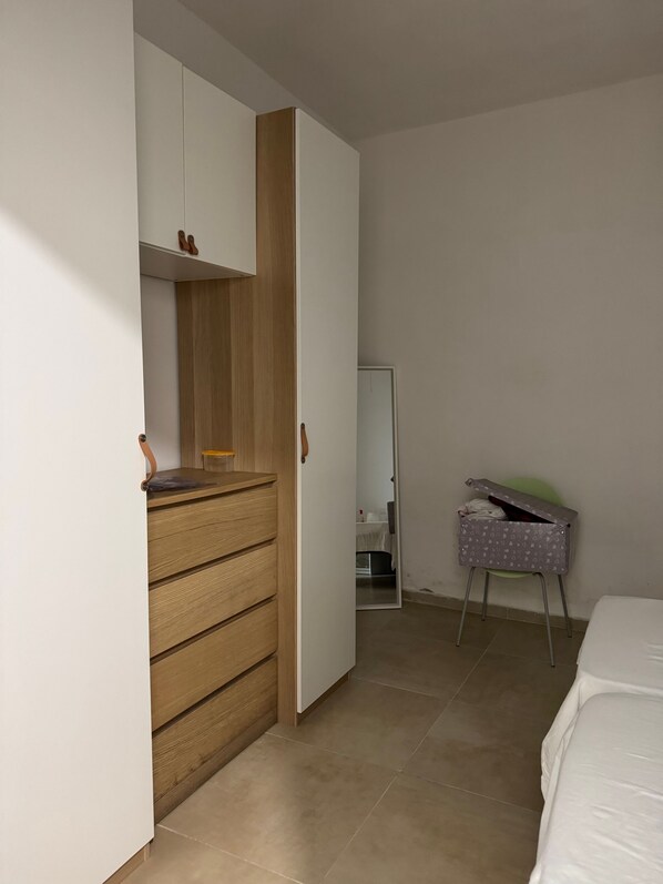 Ein Schlafzimmer mit einem Holzkoffer, einem Bett und einem kleinen Tisch mit Stuhl.