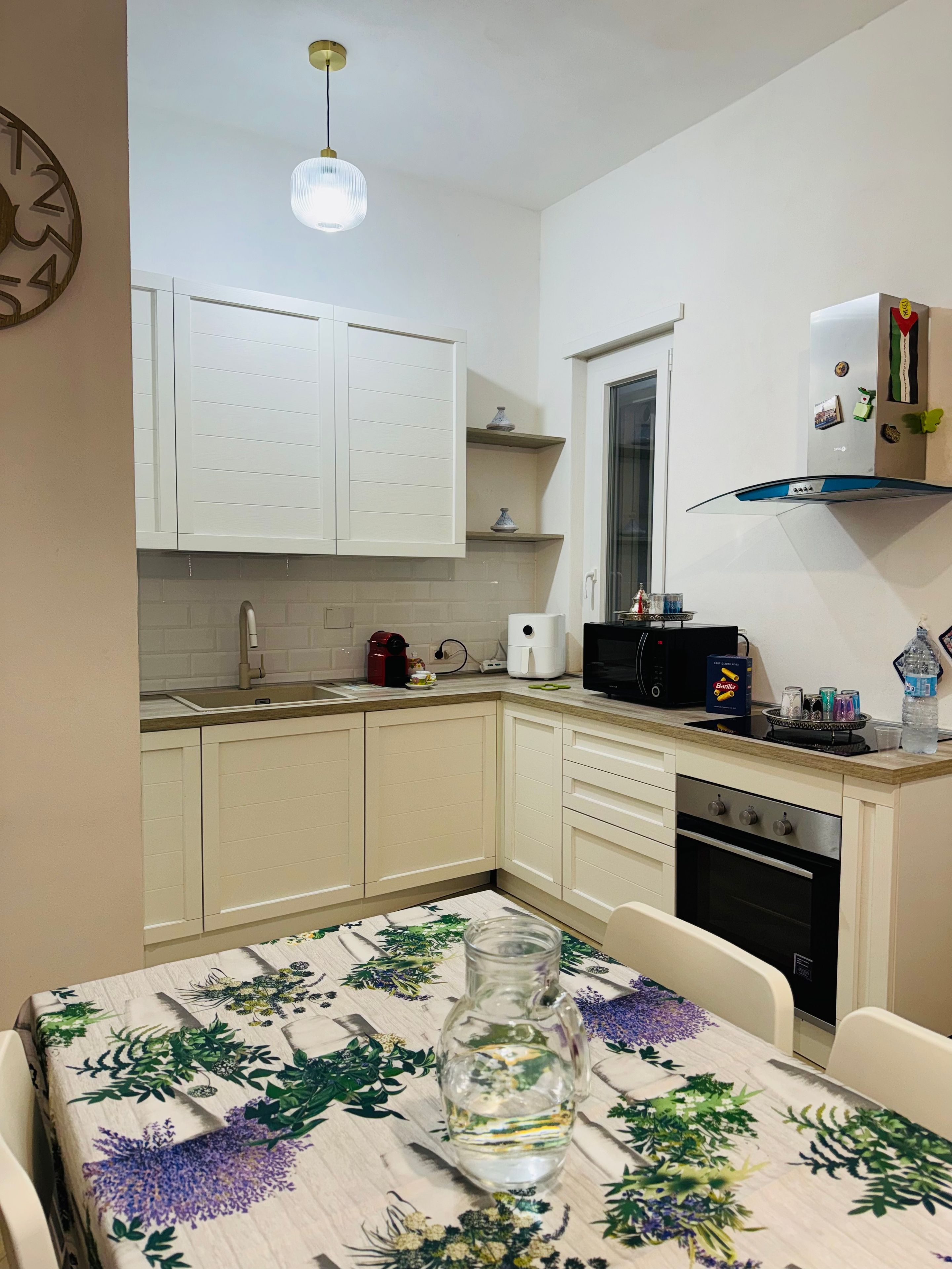 A kitchen with white cabinets, a built-in oven, and a coffee machine.