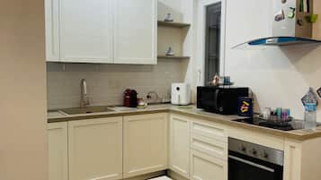A kitchen with white cabinets, a built-in oven, and a coffee machine.