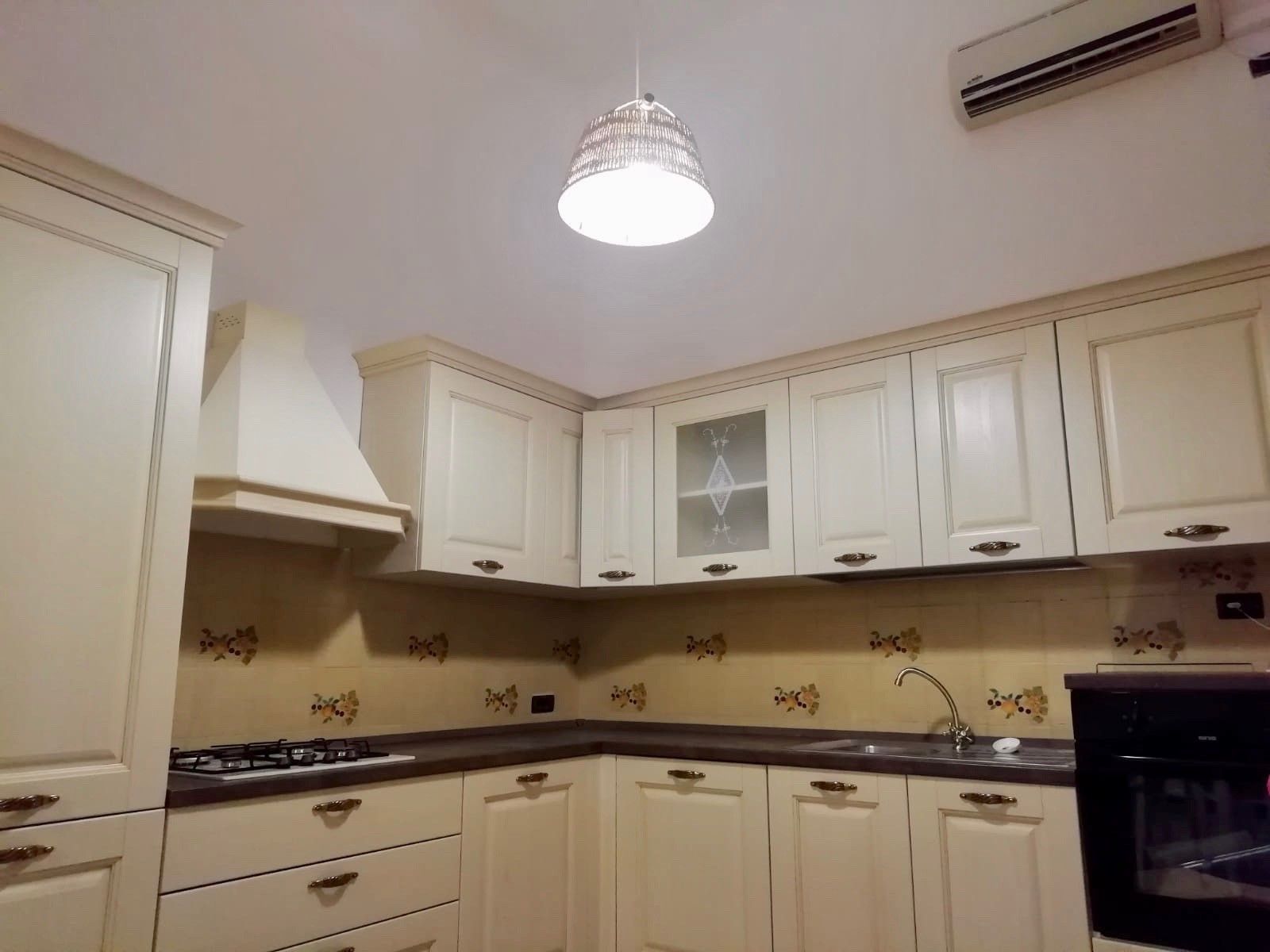 A kitchen with white cabinets, a gas stove, a sink, and a black oven.