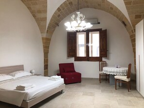 A bedroom with a bed, a red chair, a table with a chair, and a chandelier. - Holiday home 'Da Gigetto Tuturano' with private garden and Wi-Fi (Tuturano)
