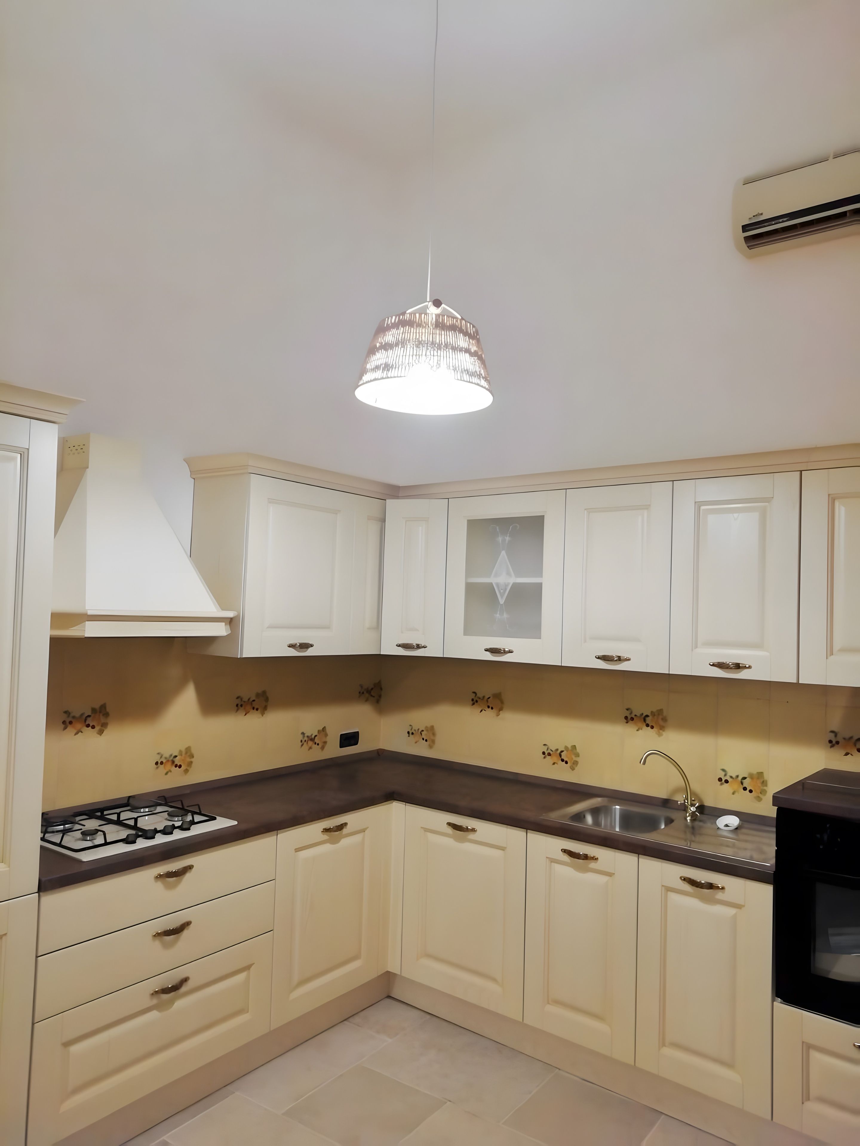 A kitchen with white cabinets, a gas stove, a sink, and a pendant light.