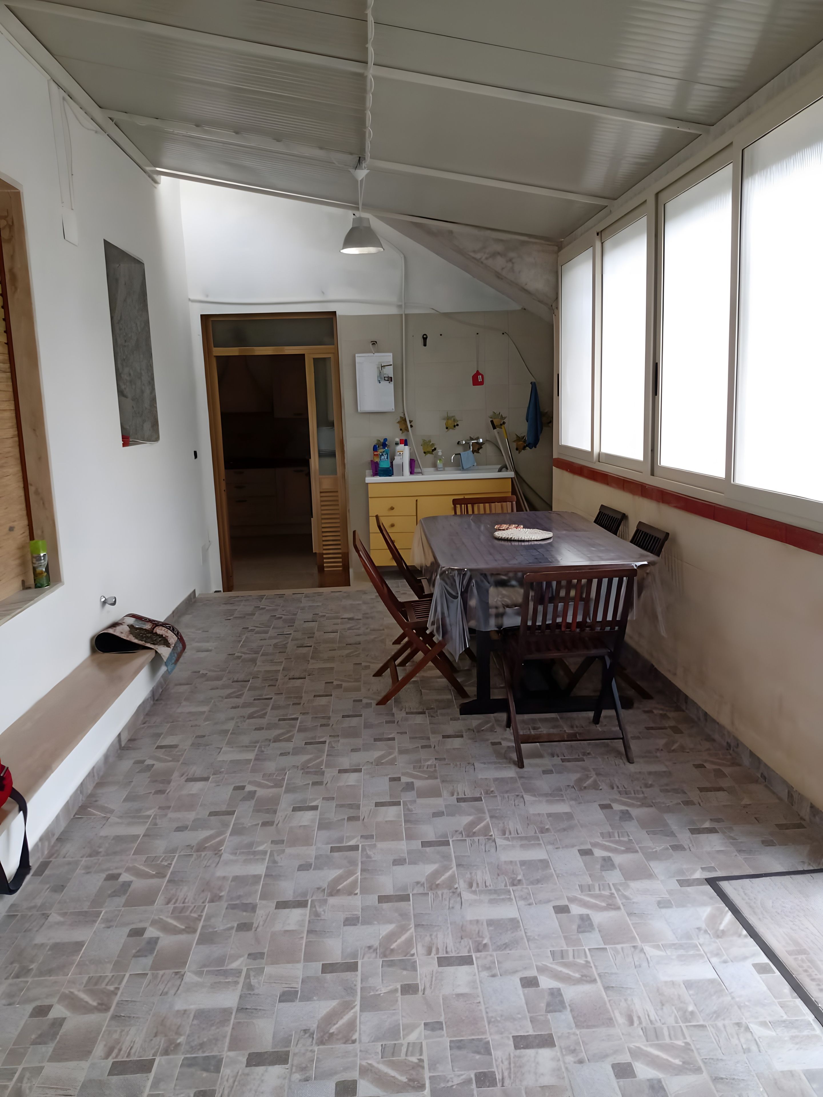 A dining area with a table and chairs, a kitchen with a sink and cabinets, and a window with a view.
