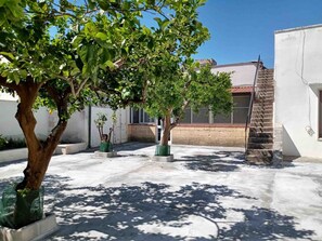 A courtyard with trees, a staircase, and a building with a tiled roof. - Holiday home 'Da Gigetto Tuturano' with private garden and Wi-Fi (Tuturano)