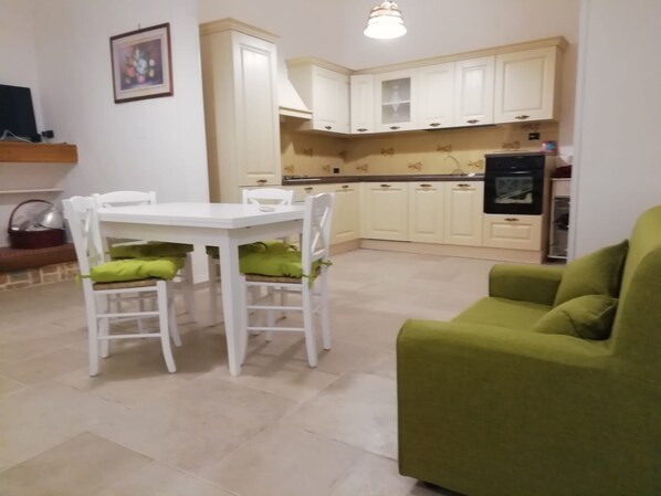 A compact living space with a dining table and chairs, a green sofa, and a kitchenette. - Holiday home 'Da Gigetto Tuturano' with private garden and Wi-Fi (Tuturano)