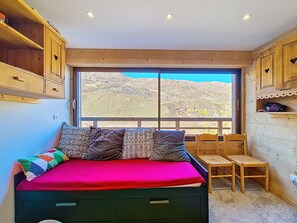 A room with a bed, a window, a chair, and wooden cabinets. - Pleasant apartment at the foot of the slopes - 4 guests (Les Menuires)