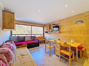 A cozy room with a sofa, a dining table, and a kitchen area. - Pleasant apartment at the foot of the slopes - 4 guests (Les Menuires)