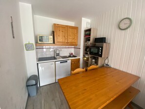 Eine kompakte Küche mit Holzschränken, einer Mikrowelle, einer Kaffeemaschine und einem kleinen Kühlschrank.