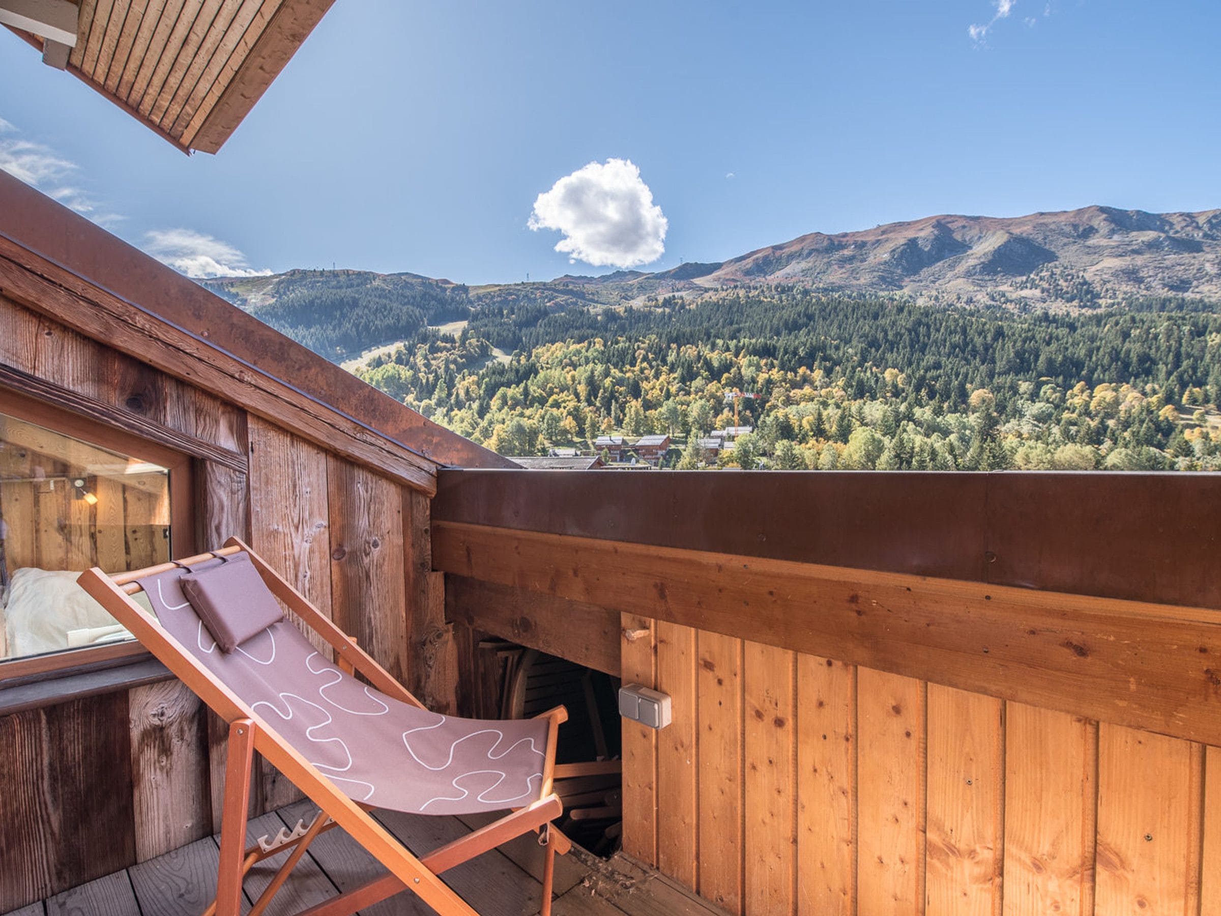 A wooden deck with a lounge chair and a view of a mountainous landscape.
