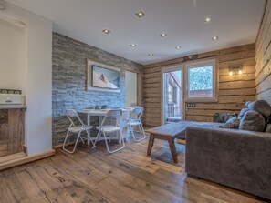 A cozy interior with a dining area, wooden walls, and a sofa. - Ski-in/ski-out apartment, mountain view - 4 guests (Méribel)