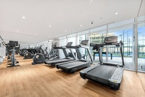 Une salle de sport équipée de plusieurs tapis de course, de vélos d’appartement et d’appareils de musculation.