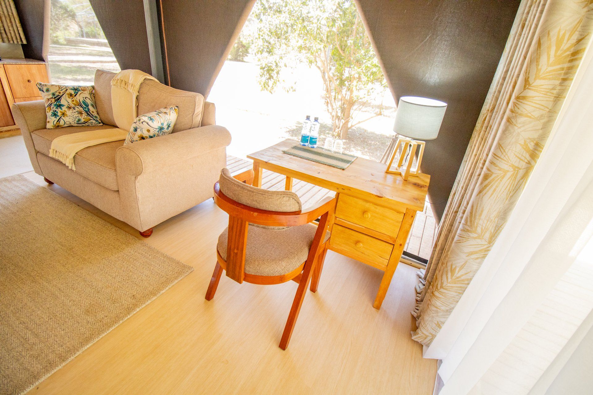 Una habitación acogedora con un sofá, un escritorio de madera y una silla.