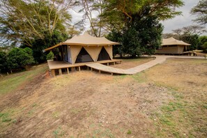A campsite with two tents, each with a wooden platform and a ramp leading to the entrance.