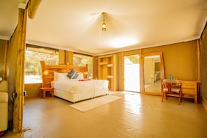 A bedroom with a wooden headboard, a bed, a nightstand, a desk, and a chair. - Nyota Springs Luxury Camp (Maasai Mara)