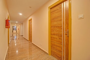 A hotel corridor with wooden doors and a fire extinguisher on the wall. - Super Townhouse Whiteridge Gachibowli  (Hyderabad)