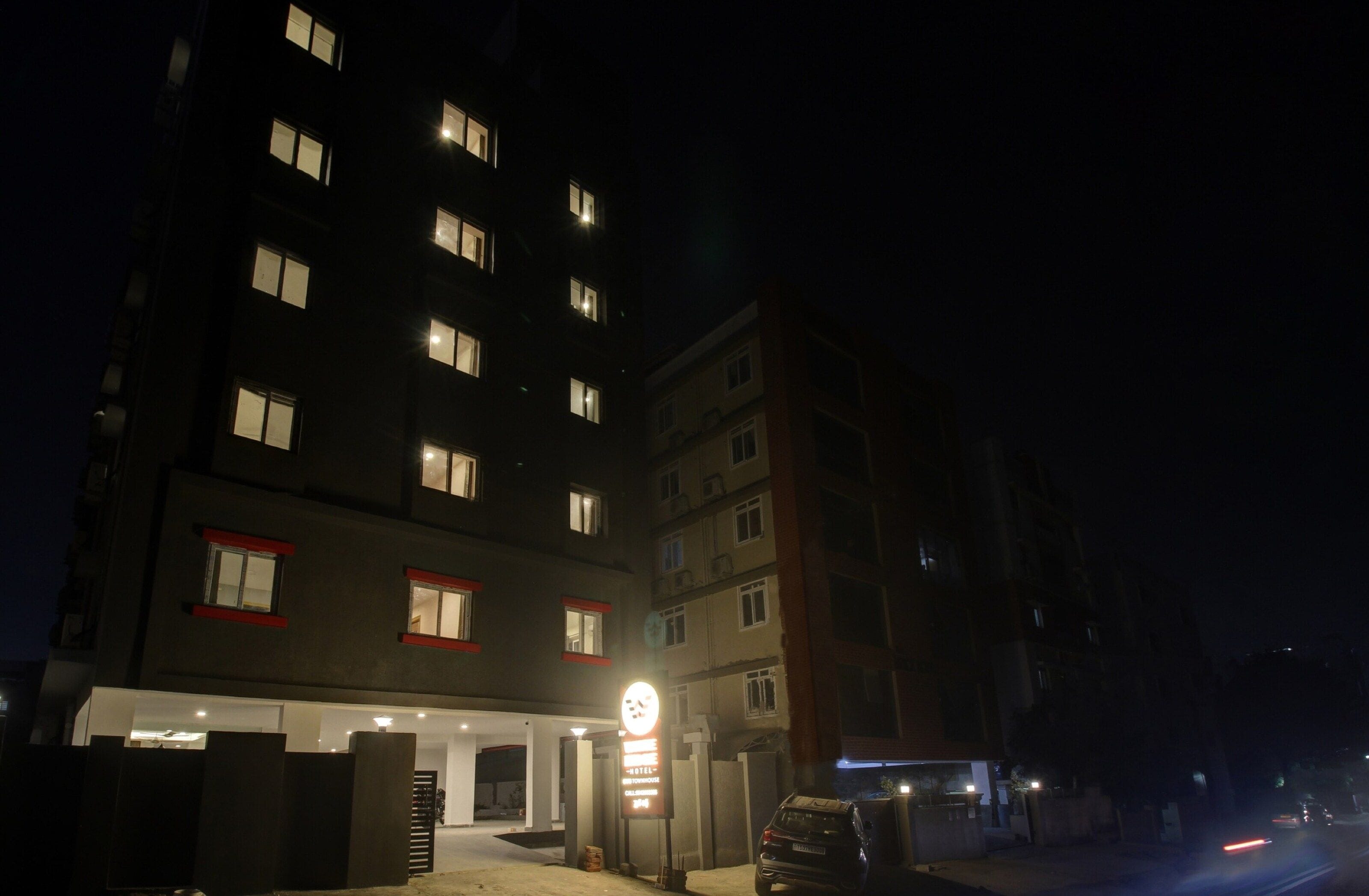 A multi-story hotel building at night with illuminated windows and a signboard.