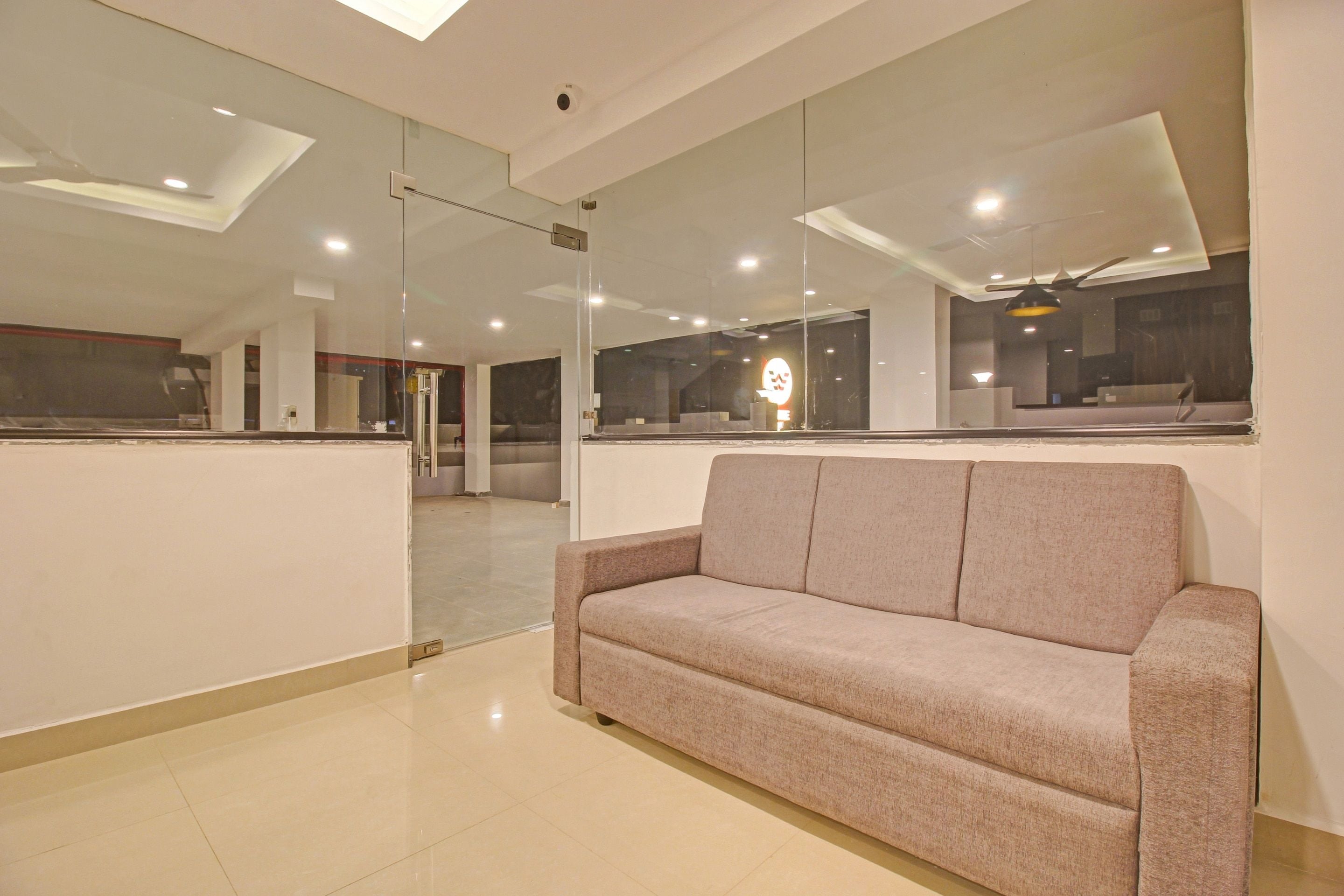 A modern interior with a sofa, glass partitions, and recessed ceiling lights.