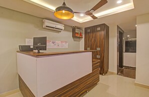 A reception desk with a computer, a ceiling fan, and an air conditioning unit. - Super Townhouse Whiteridge Gachibowli  (Hyderabad)