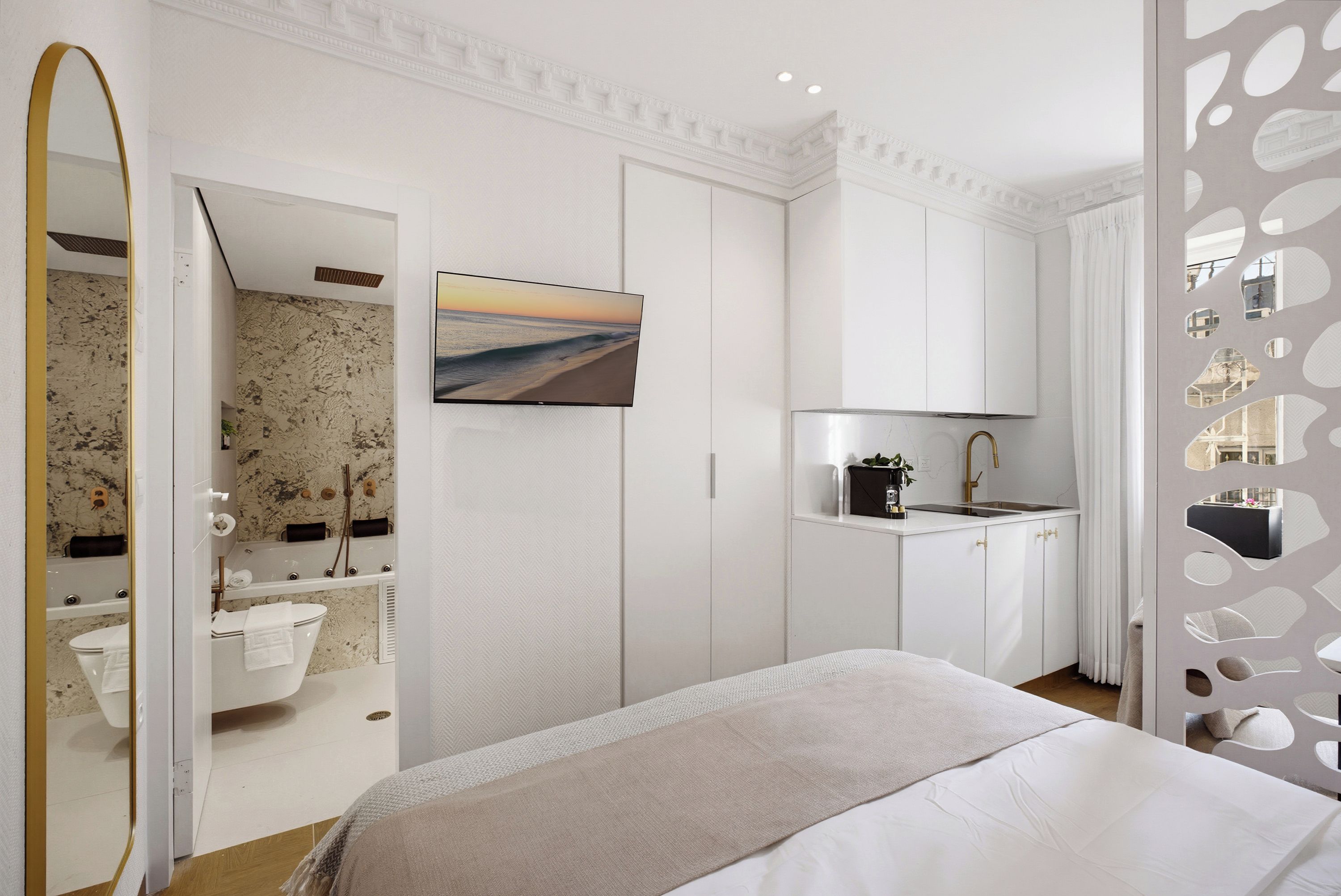 A modern bedroom with a bed, a bathroom with a bathtub, and a kitchenette.