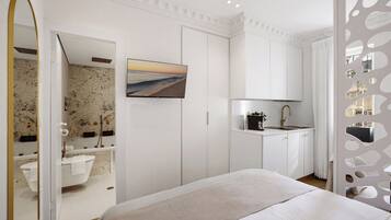 A modern bedroom with a bed, a bathroom with a bathtub, and a kitchenette.