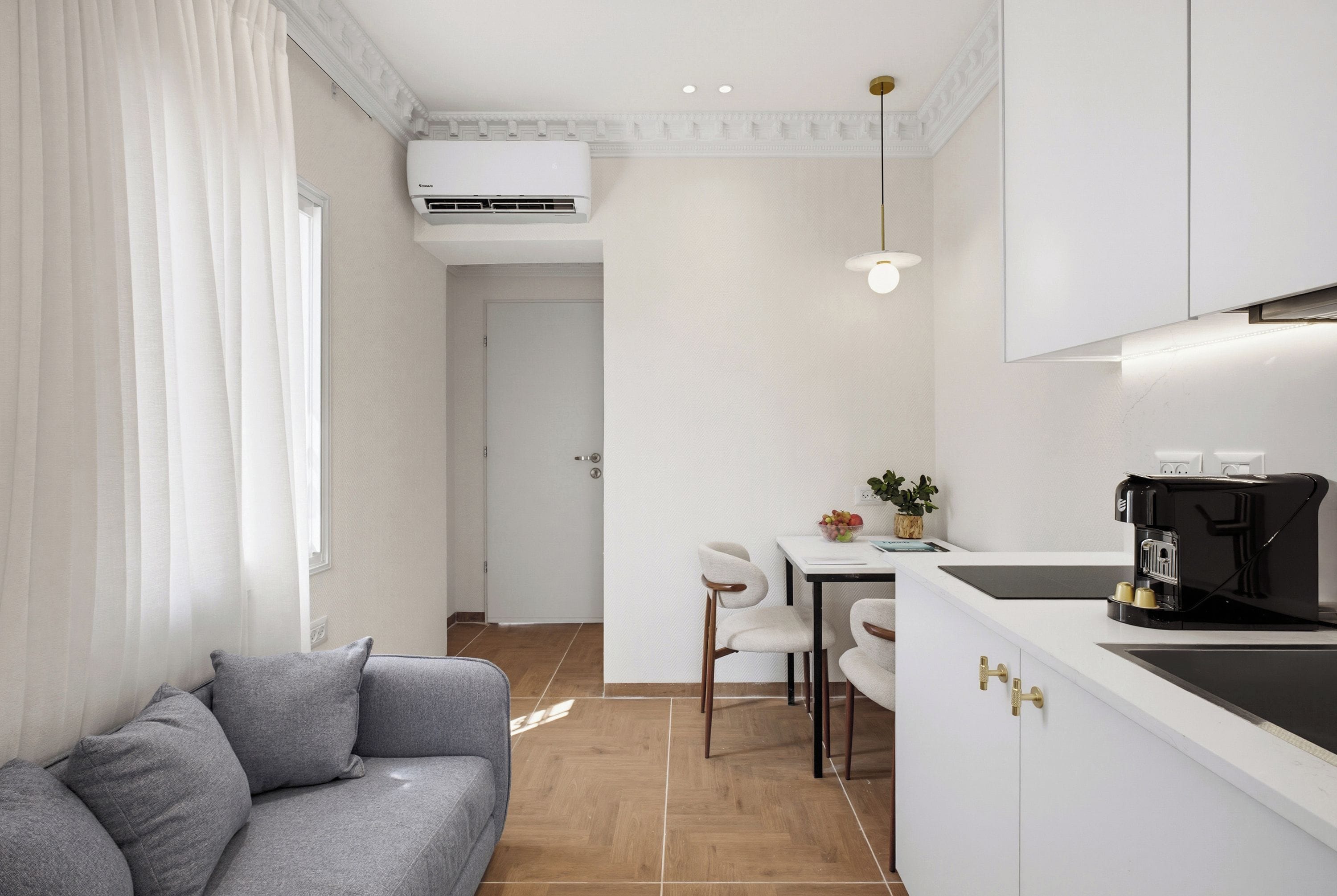 Una cocina moderna con armarios blancos, una cafetera y un comedor con mesa y sillas.