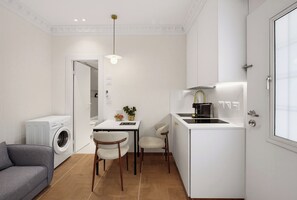 A compact kitchen with a built-in stove, a washing machine, and a dining area with chairs. - baraca botique -hamadregot 8 (Jerusalem)