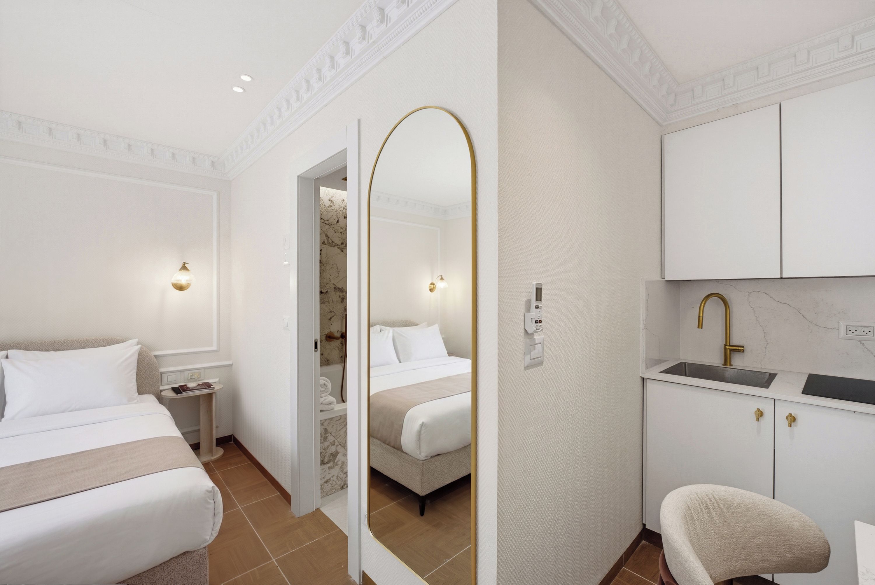 Habitación de hotel con cama, mesita de noche, espejo, armario y baño con lavamanos.