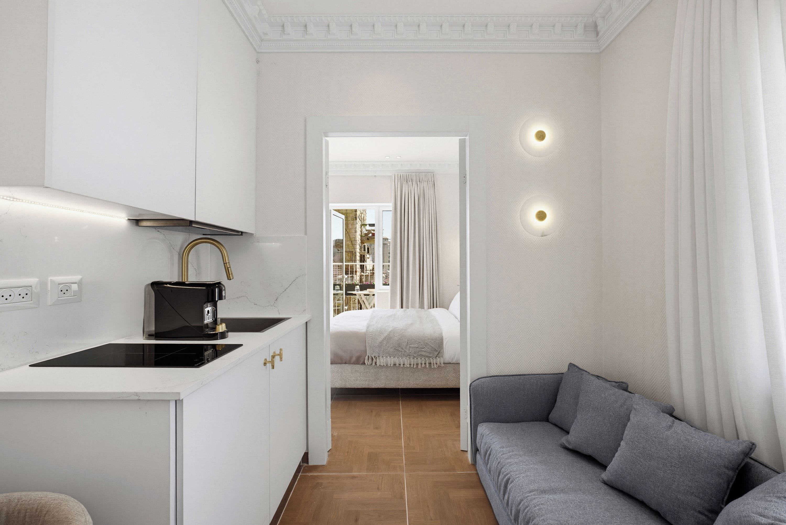 Habitación de hotel compacta con kitchenette, sofá, cama y vista a la ciudad.