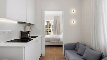 Habitación de hotel compacta con kitchenette, sofá, cama y vista a la ciudad.