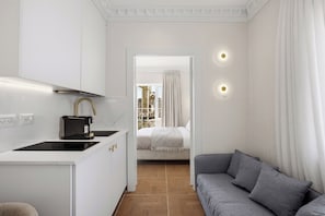 Habitación de hotel compacta con kitchenette, sofá, cama y vista a la ciudad.