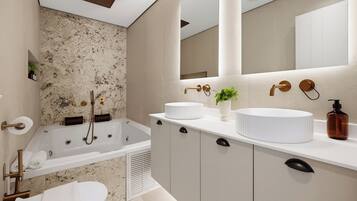 A modern bathroom with a freestanding bathtub, a toilet, and a vanity with a mirror.