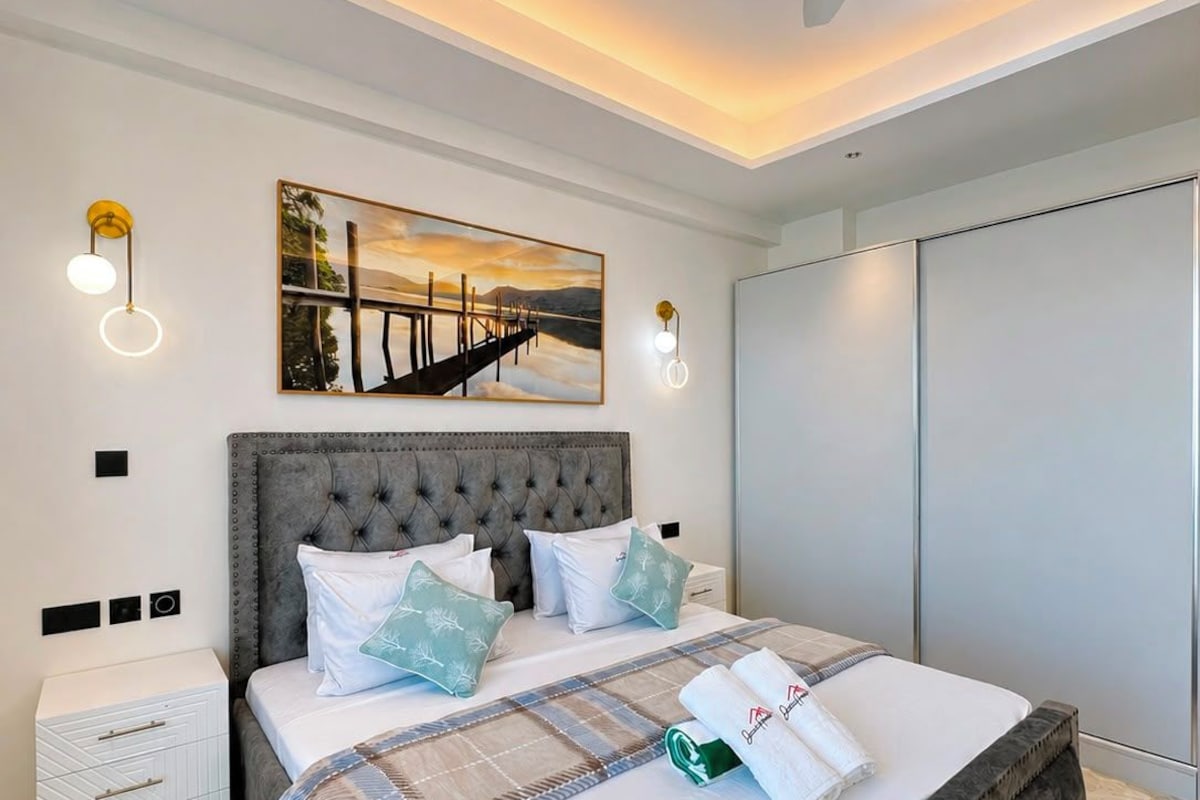 Ein Schlafzimmer mit einem großen Bett, einem Deckenventilator, Wandleuchten, einem Gemälde und einem Kleiderschrank.
