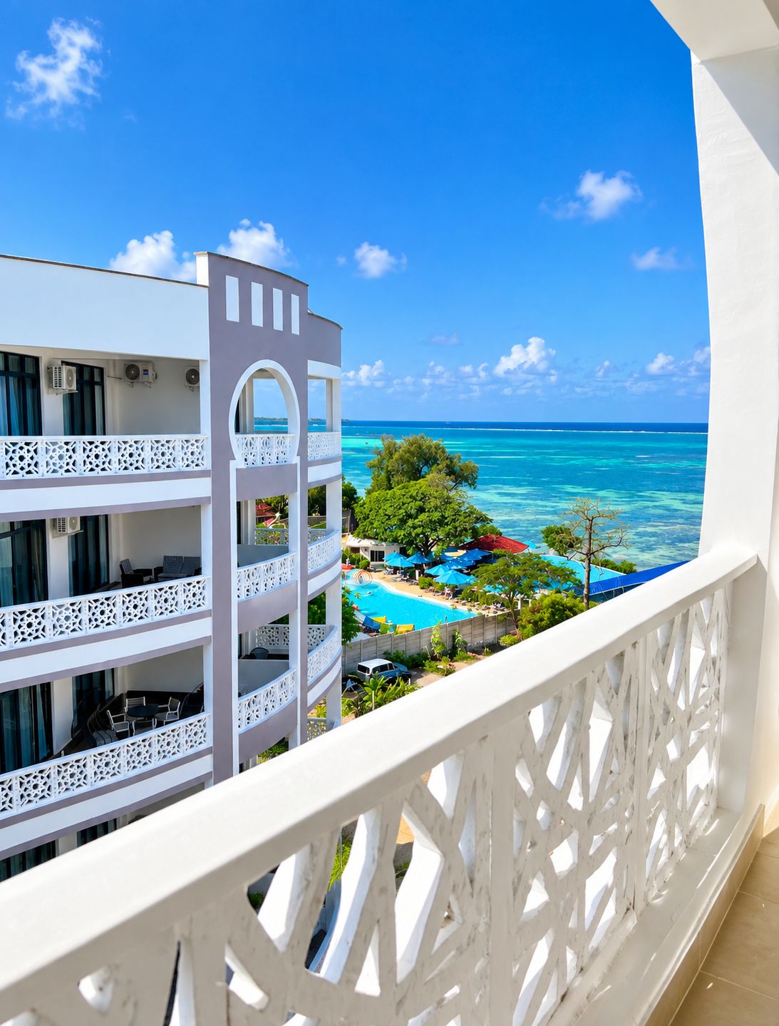 A hotel balcony with a view of a swimming pool and ocean.
